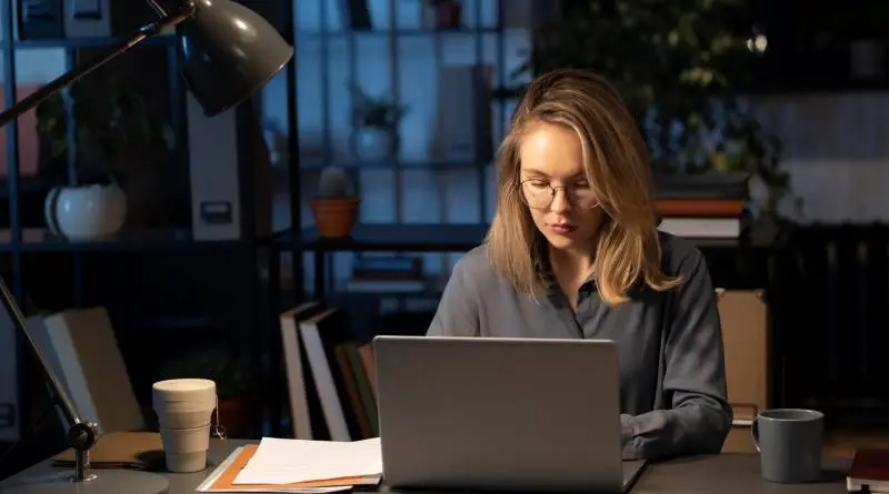 Equilibrio tra lavoro e vita privata - Immagine di giovane donna che lavora da casa con laptop.